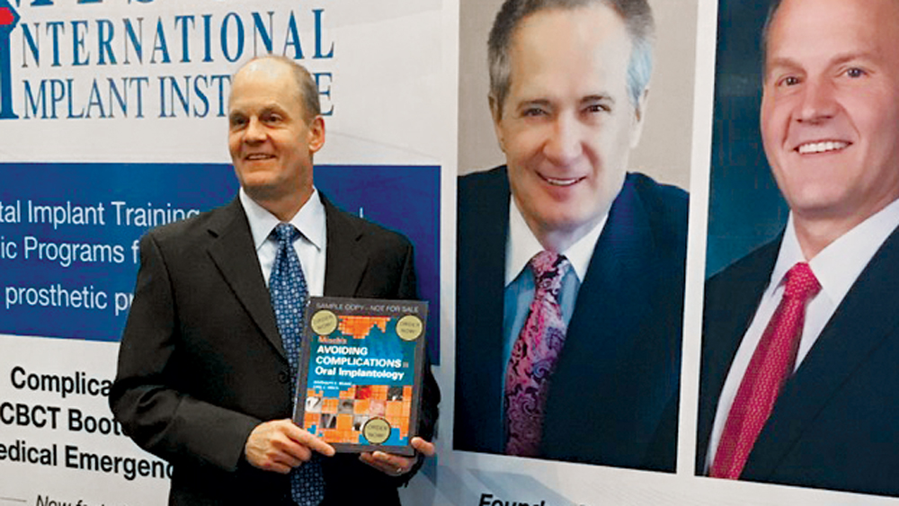 Dr. Randolph Resnik holds a copy of “Avoiding Complications in Oral Implantology,” a textbook that he and Dr. Carl E. Misch coauthored.