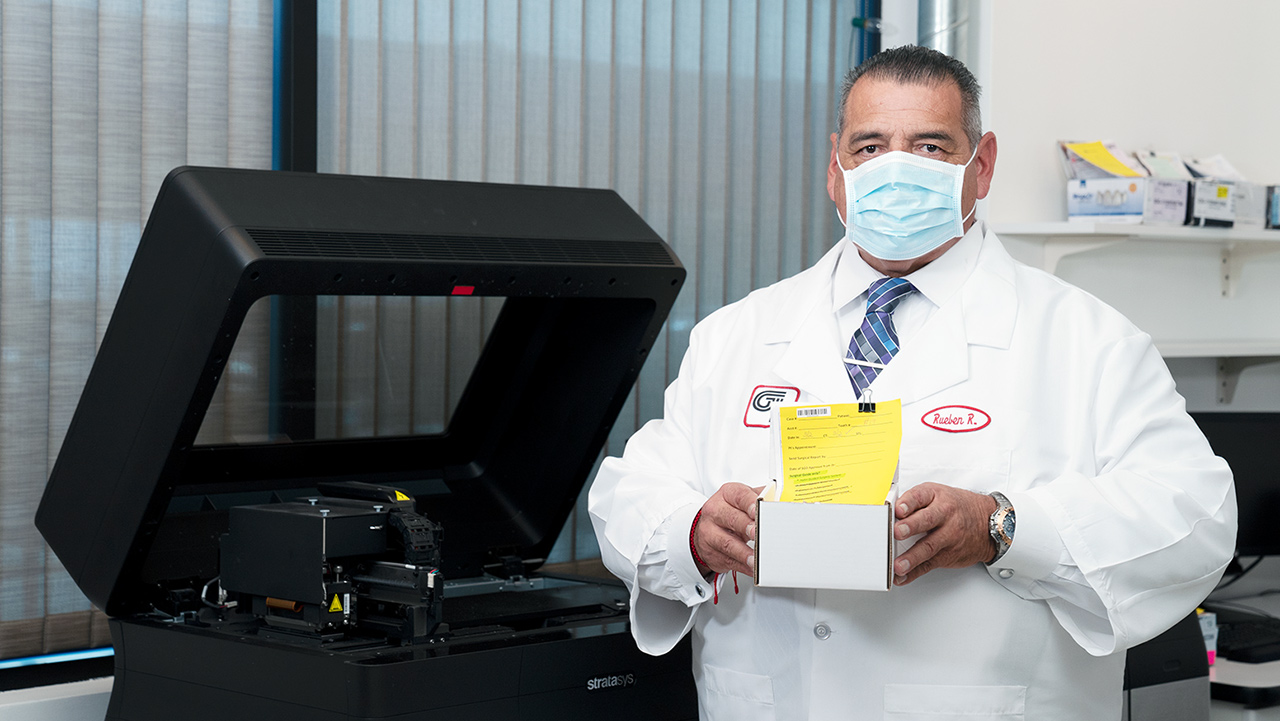 Romero, Standing in front of the cutting-edge 3D printers used in the fabrication of surgical guides at Glidewell