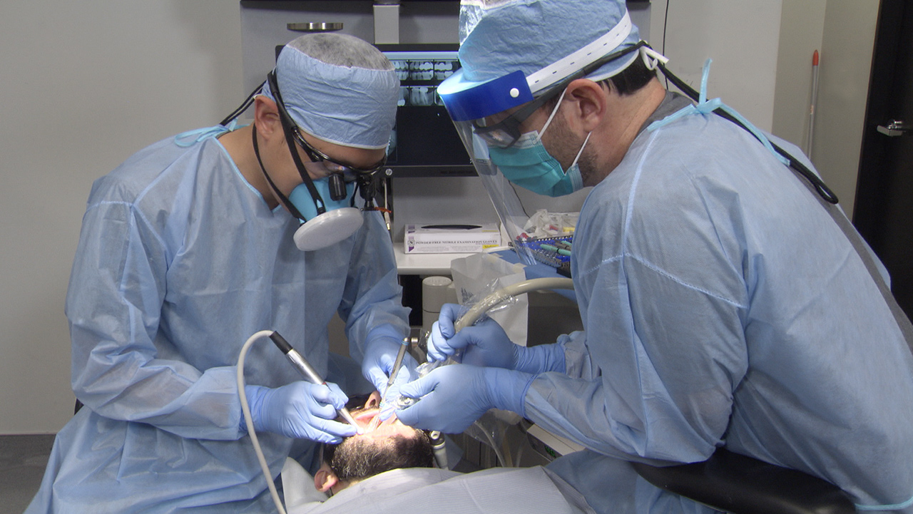 Shown here, Dr. Chi and Will Schmidt, RDA, wear PPE during a chairside procedure.