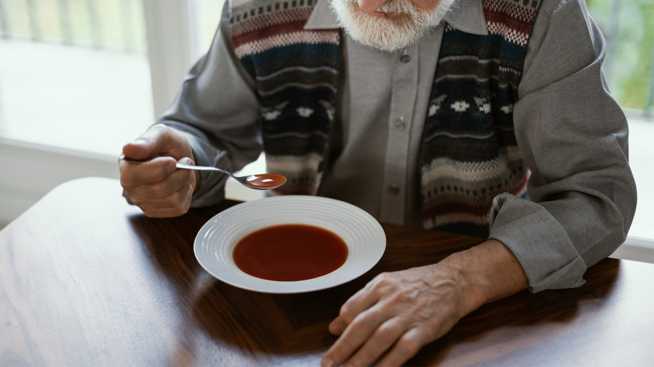 Close older lonely man eating soup