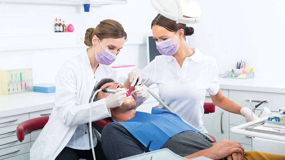 two women dentists cleaning patient's teeth