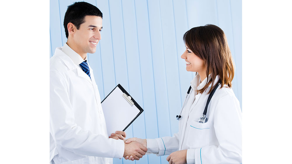 man in lab coat shaking hands with woman in lab coat