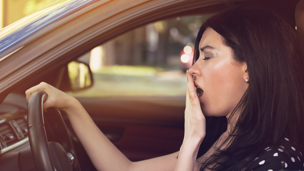 Woman yawning inside her car