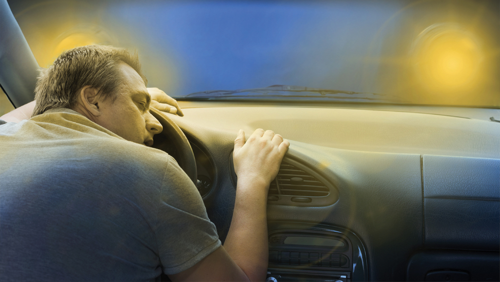 Man sleeping on his car driver wheel