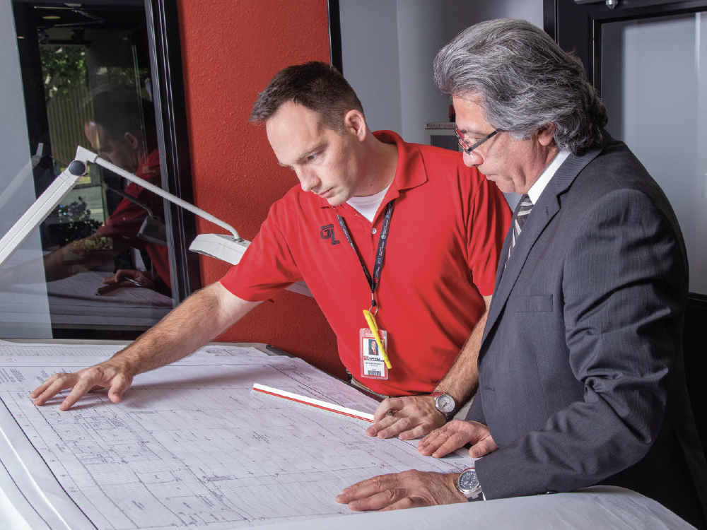 Two Glidewell employees looking at drafting plans