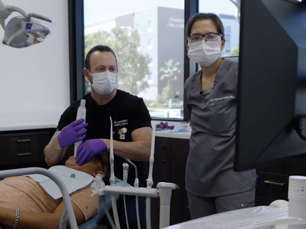 Dental staff using the intraoral scanner on a patient while observing a computer monitor