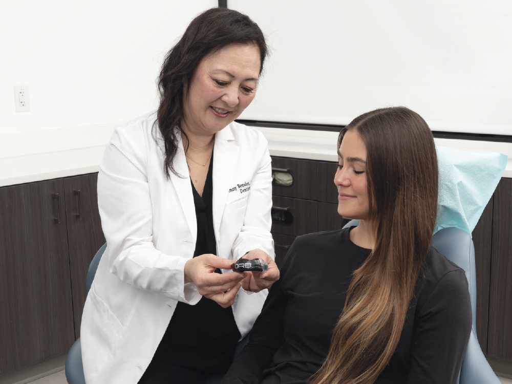 A dentist shows a patient the ORB Sport mouthguard