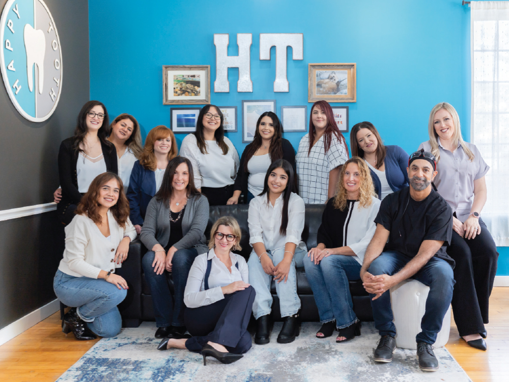 Group portrait of the Happy Tooth dental team posing in their office lobby.