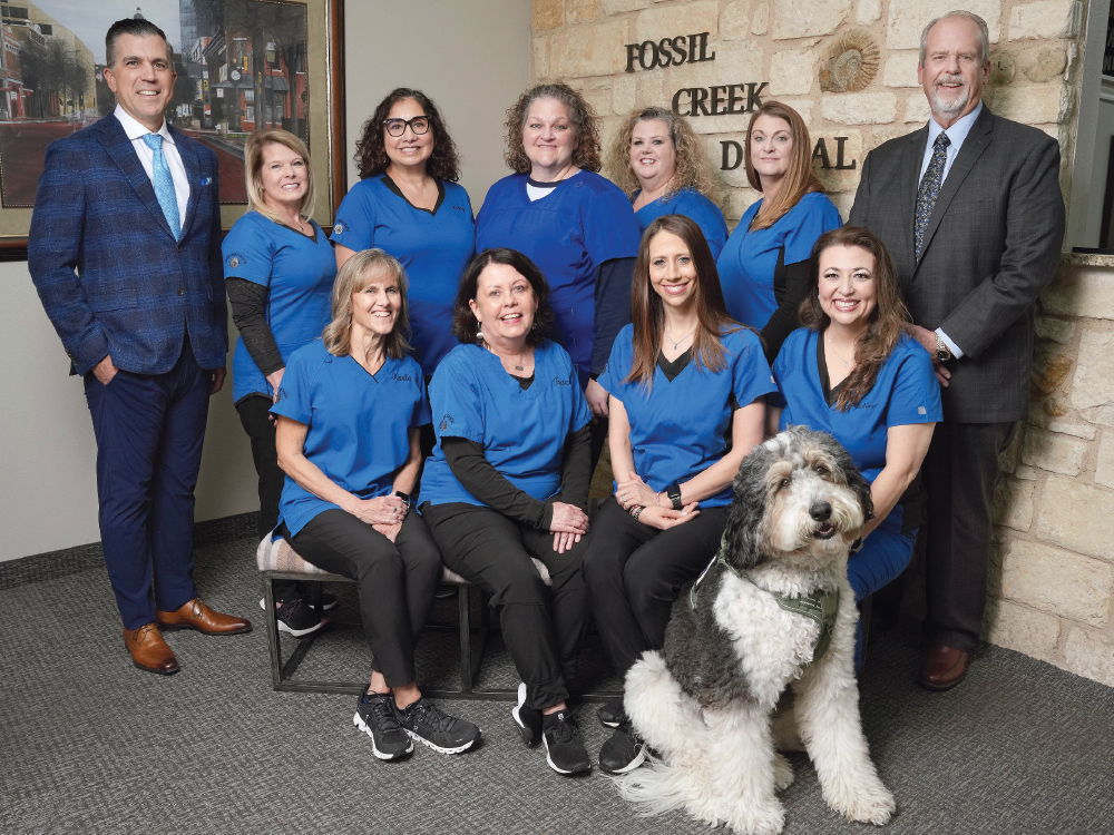 Group portrait of the Fossil Creek Dental team posing in their office with a therapy dog.