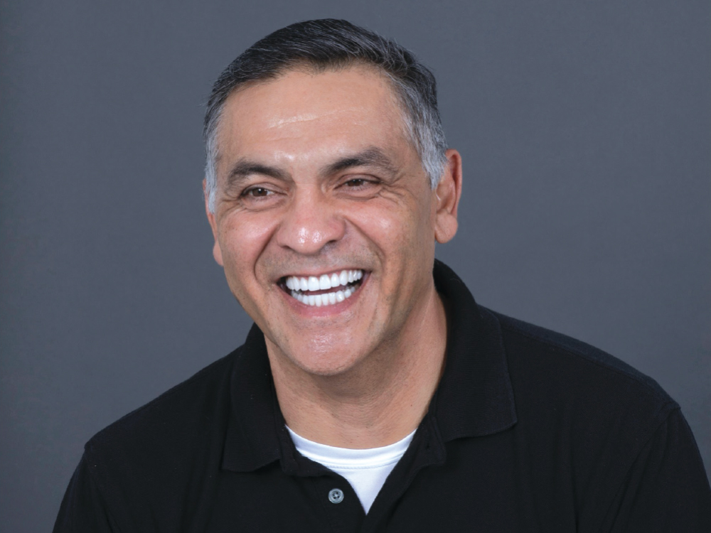 Portrait of a smiling male patient showing his fully restored smile following complete full-mouth rehabilitation.